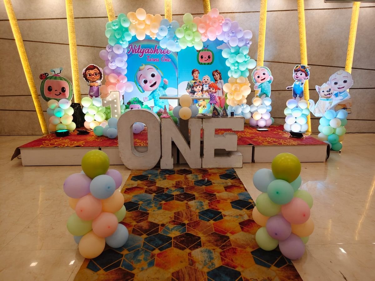 Cocomelon theme first birthday stage decoration with pastel balloon arch by Magic Moment Events Planner