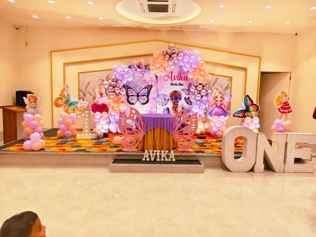 Fairy and butterfly theme birthday stage decoration with pastel balloons and cake table