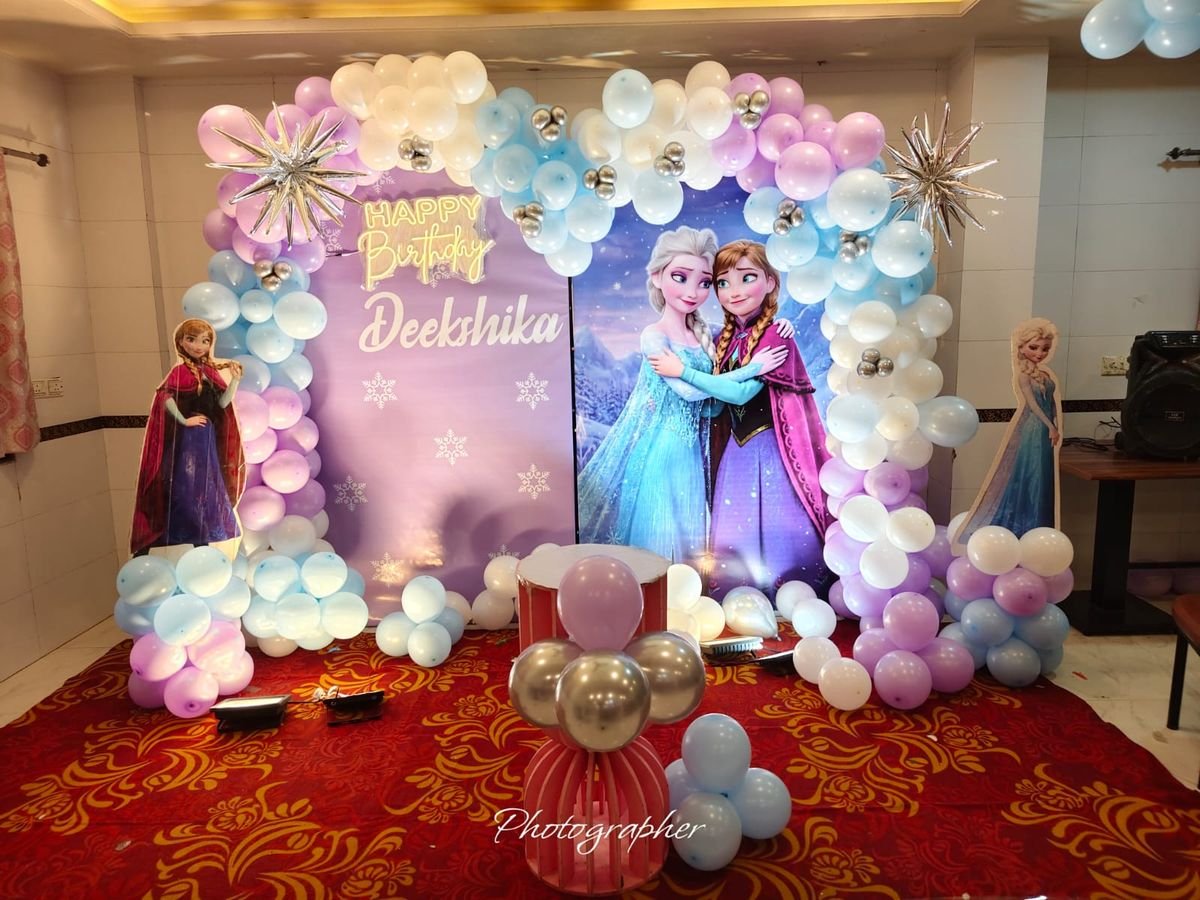 Frozen theme birthday decoration with blue white balloon arch and neon happy birthday sign
